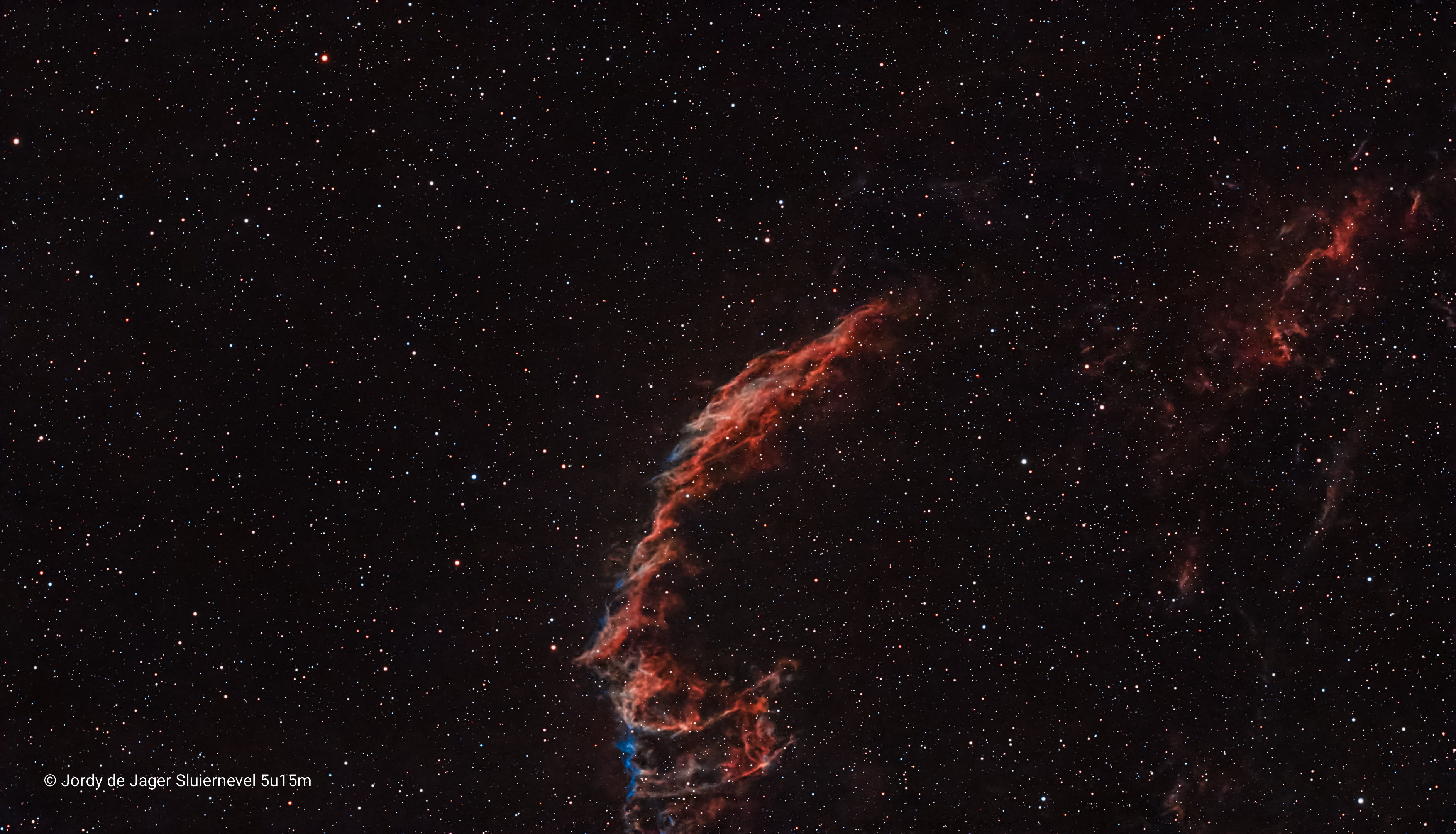 The Eastern Veil Nebula NGC 6992/C33 Inzoomen op een kosmische explosie! Dit deel van het gigantische supernovarestant in de Zwaan (Cygnus) staat bekend om zijn ongelooflijk gedetailleerde, bijna vloeibaar lijkende structuren. Door ruim 2 uur aan data op dit specifieke paneel te verzamelen, komen de flinterdunne schokgolven van gas - die met duizenden kilometers per seconde door de ruimte razen - prachtig naar voren. Het contrast tussen de gloeiende rode waterstofdraden en het subtiele blauw/groene zuurstofgas laat perfect zien hoe de energie van een ontplofte ster na duizenden jaren nog steeds interstellair gas aan het oplichten is. Capture details: Telescoop: Dwarf 3 Smart Telescope Integratietijd: 2 uur en 14 minuten